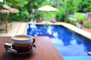 蓝赛特海滩菠萝岛旅馆的坐在游泳池畔的桌子上喝杯咖啡