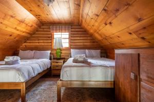 two beds in a log cabin bedroom with wooden ceilings at Chair 9 Chalet in Big Bear Lake