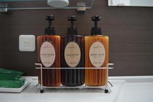 four orange bottles sitting on a rack on a sink at Hotel Route-Inn Shimizu Inter in Shizuoka