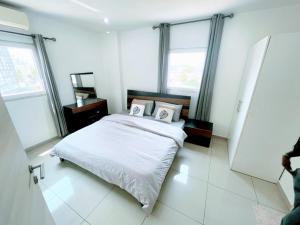 阿克拉Chic 1BR Apt with Pool, High-speed Internet at The Gallery, 10 mins from Airport, 5mins from Major Restaurants and Malls的白色卧室配有床和2个枕头 更多12张照片