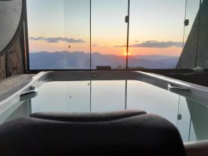 a hot tub in a room with a view of the sunset at Chalé canaã in Passa Quatro