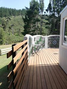 a wooden deck with a table and a chair on it at Old Mountain Road Retreat in Raglan