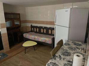 a kitchen with a refrigerator and a table and a bed at F2 Maison avec jardin à Constantine in Hamma Bouziane