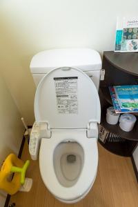 une salle de bain avec des toilettes blanches dans une chambre dans l'établissement 猫宿 Muribushi-inn, à Motobu