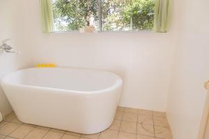 La salle de bains est pourvue d'une baignoire blanche et d'une fenêtre. dans l'établissement 猫宿 Muribushi-inn, à Motobu 7 autres photos