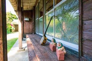 une terrasse couverte d'une maison dotée d'une statue de clown. dans l'établissement 猫宿 Muribushi-inn, à Motobu