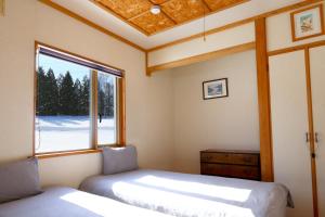two beds in a room with a window at Ronin Lodge in Furano