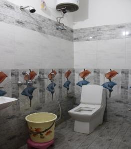 baño con aseo y lavabo con pájaros en la pared en Hotel Singh Residency, en Varanasi