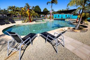 two chairs sitting in front of a swimming pool at Lakeside Forster Holiday Park in Forster