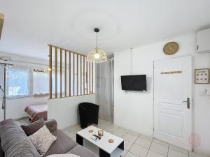 un salon avec un canapé et une télévision dans l'établissement Appartement F1 avec Terrasse et Clim, à 650m des Thermes - Lamalou-les-Bains - FR-1-451-191, à Lamalou-les-Bains