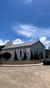 a white church with a car parked in front of it at Apê do NADINHO in Caparaó Velho +3 photos