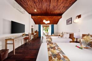 una camera d'albergo con due letti e una TV a schermo piatto di Vinh Hung Riverside Resort & Spa a Hoi An