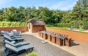 a patio with chairs and a table and a brick wall at Stunning Home In Ulfborg With Sauna in Ulfborg