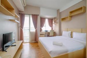une chambre d'hôtel avec un lit et une télévision dans l'établissement Cozy Stay and Warm Studio Apartment at Margonda Residence 5 By Travelio, à Depok