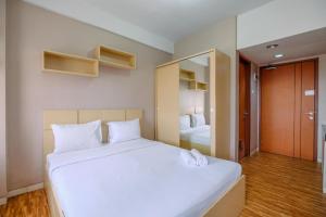 une chambre avec un grand lit blanc et un miroir dans l'établissement Cozy Stay and Warm Studio Apartment at Margonda Residence 5 By Travelio, à Depok 14 autres photos
