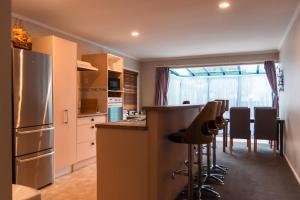 a kitchen with a counter and a bar with chairs at Observation Holiday Home in Paraparaumu Beach