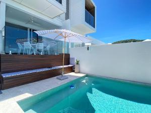 Una piscina con una sombrilla al lado de una casa. en Casa del Sol, en Nelly Bay