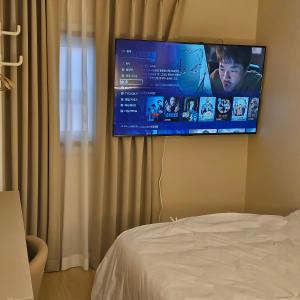 a flat screen tv hanging on a wall next to a bed at Parvus Sella Seongsu in Seoul