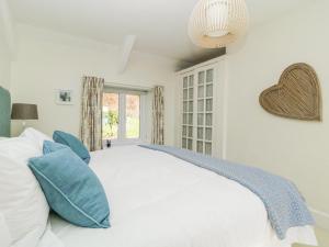 a bedroom with a large white bed with blue pillows at Clamoak Cottage in Yelverton
