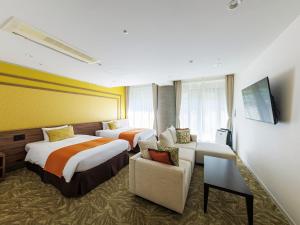 a hotel room with two beds and a couch at WeBase KAMAKURA in Kamakura