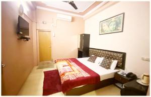 una camera da letto con un letto e una televisione di A PREMIUM VARANASI HOTEL D - S - R E S I D E N C Y - fully Air Conditioned hotel at Prime Location - Hygiene & Spacious Room - with wifi Facilities - BEST HOTEL IN VARANASI a Varanasi