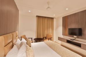 a hotel room with a bed and a flat screen tv at Kongu Residency in Karūr