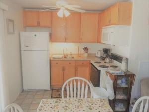 een keuken met houten kasten en een witte koelkast bij Sea Breeze W007 Wonderful Beachfront Oceanfront property for the whole family 1897 in Wells