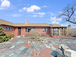 a red house with a stone patio in front of it at Seacoast Sanctuary Warm and inviting cottage with uninterrupted oceanfront 1914 in York