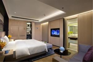 a bedroom with a large bed and a living room at Mercure Dalian City Center in Dalian