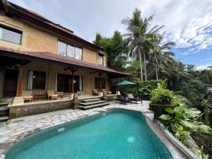 ウブドにあるSakti Garden Resort & Spaの家の前にスイミングプールがある家