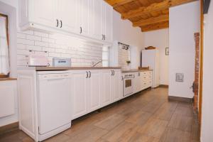 a kitchen with white cabinets and a wooden floor at Béke Vendégház in Hollókő