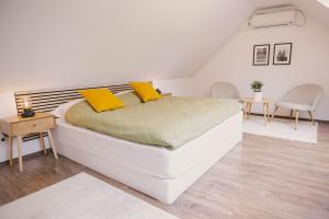 a white bedroom with a large bed with yellow pillows at Béke Vendégház in Hollókő