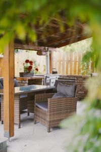 a patio with wicker chairs and a table and a kitchen at Béke Vendégház in Hollókő +5 photos