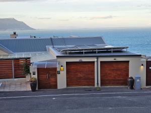a house with two garage doors and the ocean at Mariner Guesthouse & Villa in Simonʼs Town