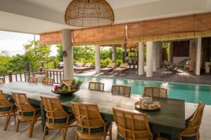 an outdoor dining area with a table and chairs and a pool at Adila Bali in Uluwatu