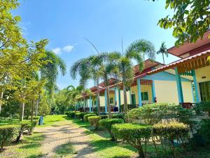 a row of houses with palm trees in a yard at Baanklongkok in Ban Map Khangkhao
