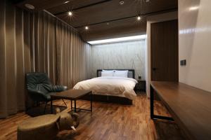 a bedroom with a bed and a chair and a table at Hotel CL in Hanam