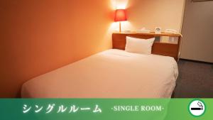 御坊にあるホテルグリーンヒル御坊駅前のベッドルーム1室(壁にランプ付きの白いベッド1台付)