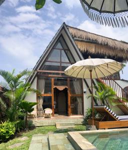 a house with a pool and an umbrella at The Phalosaa Villa in Ngaglik