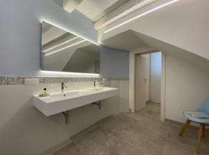 a white bathroom with a sink and a mirror at Archè in Syracuse