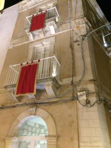 a building with two red towels hanging from windows at Archè in Syracuse