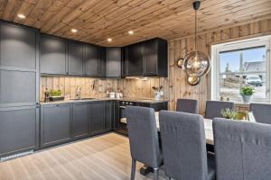 a kitchen with black cabinets and a wooden ceiling at Cozy Cabin Retreat in Lygna Jaren, Norway - Private Entrance BBQ Area in Jaren +10 photos