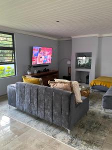 Una sala de estar con un sofá y un televisor de pantalla plana. en Bridgelamour Guest house1, en Hartbeespoort