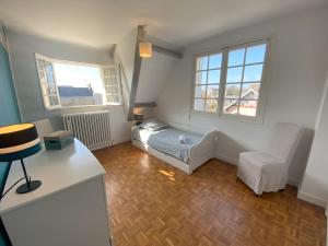 a room with a bed and a chair and windows at Le Moulin in Saint-Pair-sur-Mer