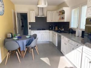 a kitchen with white cabinets and a table and chairs at Le Moulin in Saint-Pair-sur-Mer
