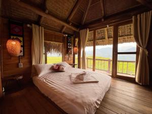 a bedroom with a bed and a large window at Pu Luong Serenity Lodge in Pu Luong