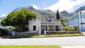 a white house with mountains in the background at Mountainside Beach House in Hermanus