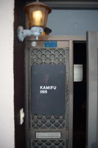 a sign for kamiu inn on a wall with a light at Kamifu INN in Kami-furano