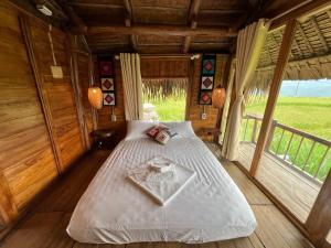 ein Schlafzimmer mit einem Bett in einem Holzhaus in der Unterkunft Pu Luong Serenity Lodge in Pu Luong