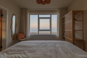 Un dormitorio con una cama grande y una ventana en Casa Buena Vista, en Egmond aan Zee